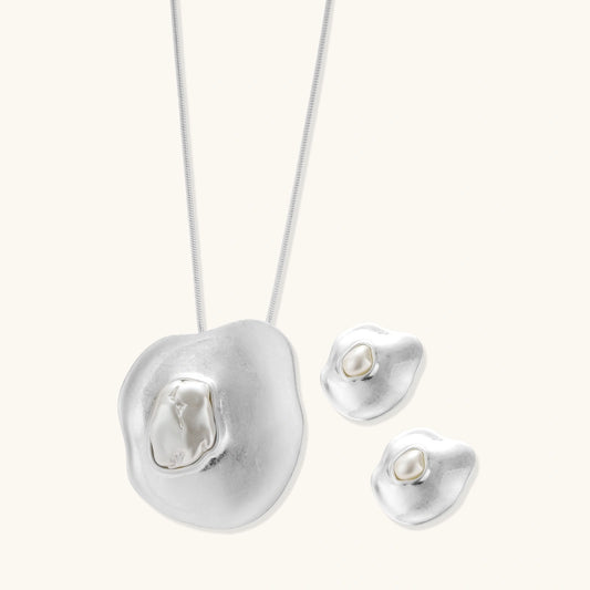 Organic curved earrings and necklace featuring baroque pearls in eco-zinc alloy settings on neutral background
