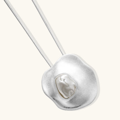 Organic curved earrings and necklace featuring baroque pearls in eco-zinc alloy settings on neutral background