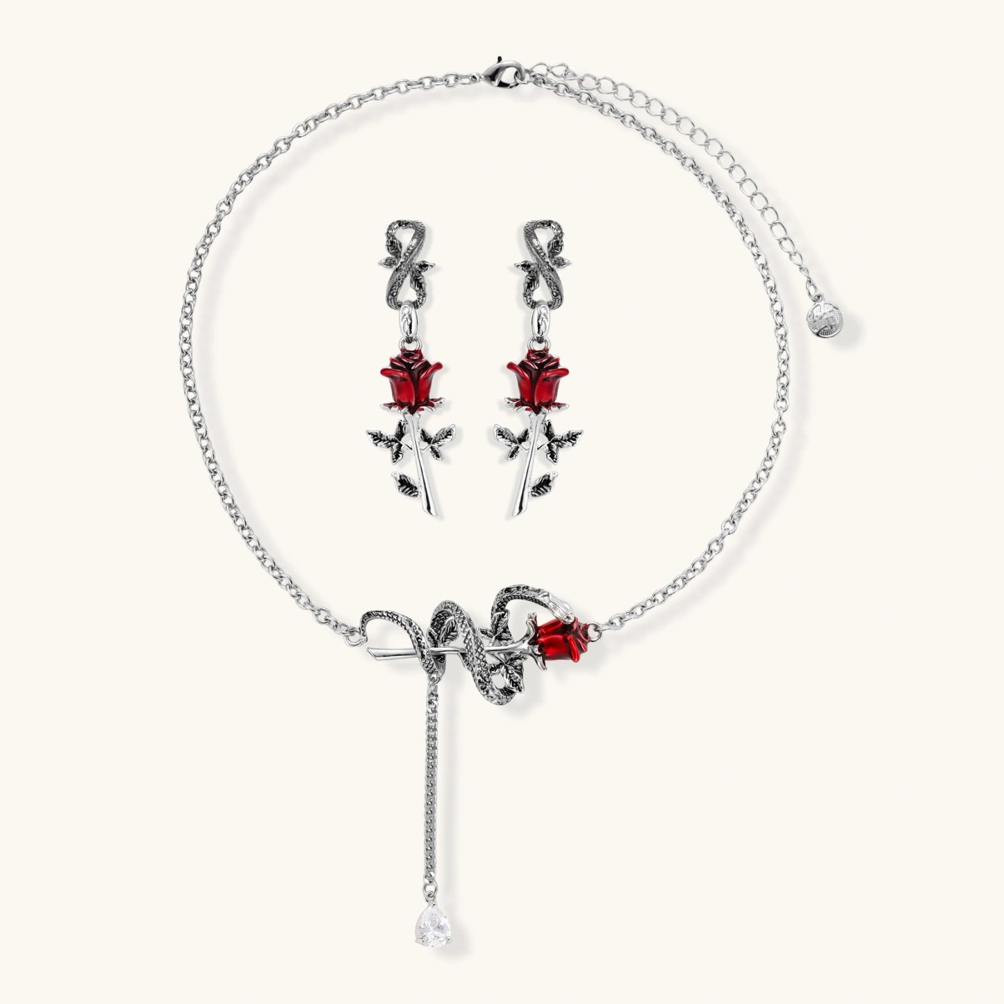 Gothic jewelry set with silver snake designs holding red enamel roses, featuring detailed leaf stems on cream background
