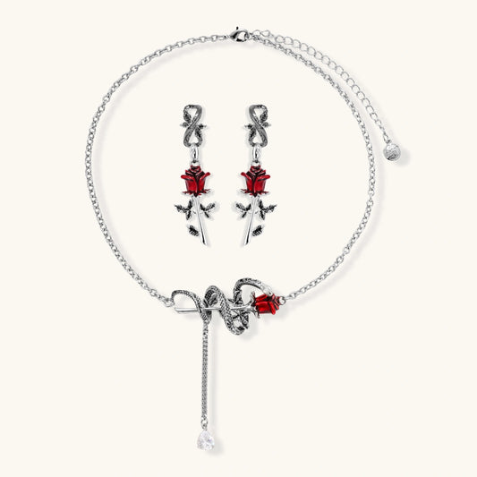Gothic jewelry set with silver snake designs holding red enamel roses, featuring detailed leaf stems on cream background