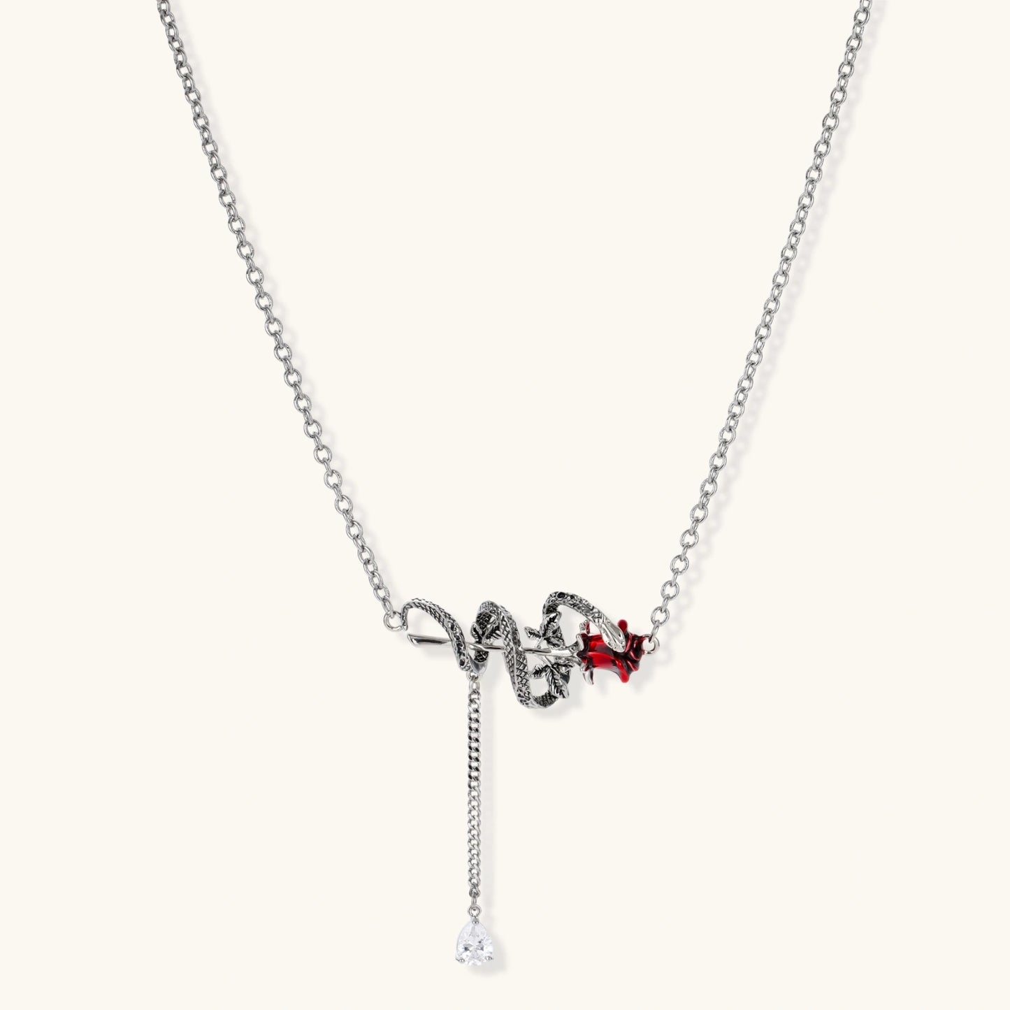 Gothic jewelry set with silver snake designs holding red enamel roses, featuring detailed leaf stems on cream background