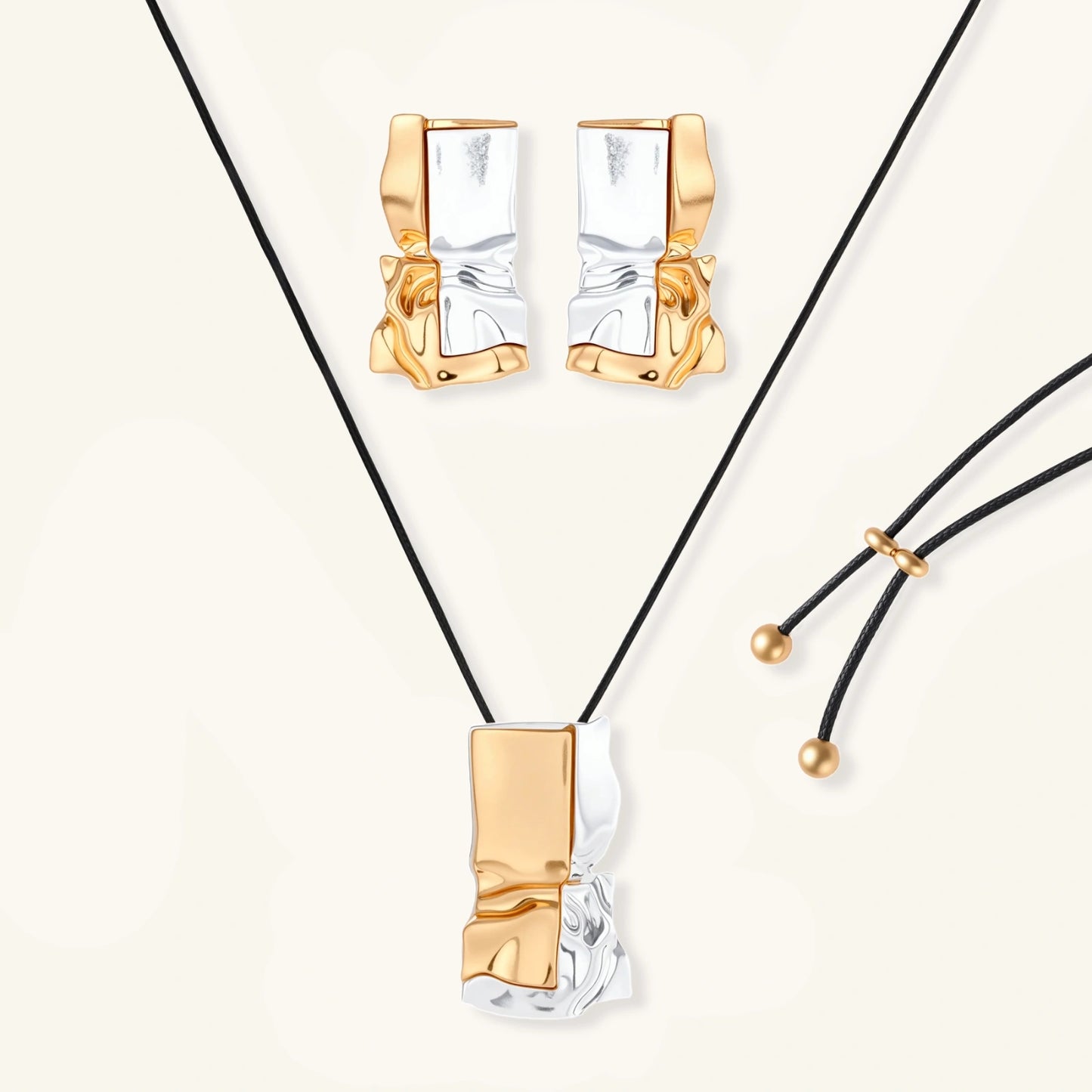 Modern jewelry set with abstract gold and silver pendant on black cord necklace plus matching geometric earrings on white background.