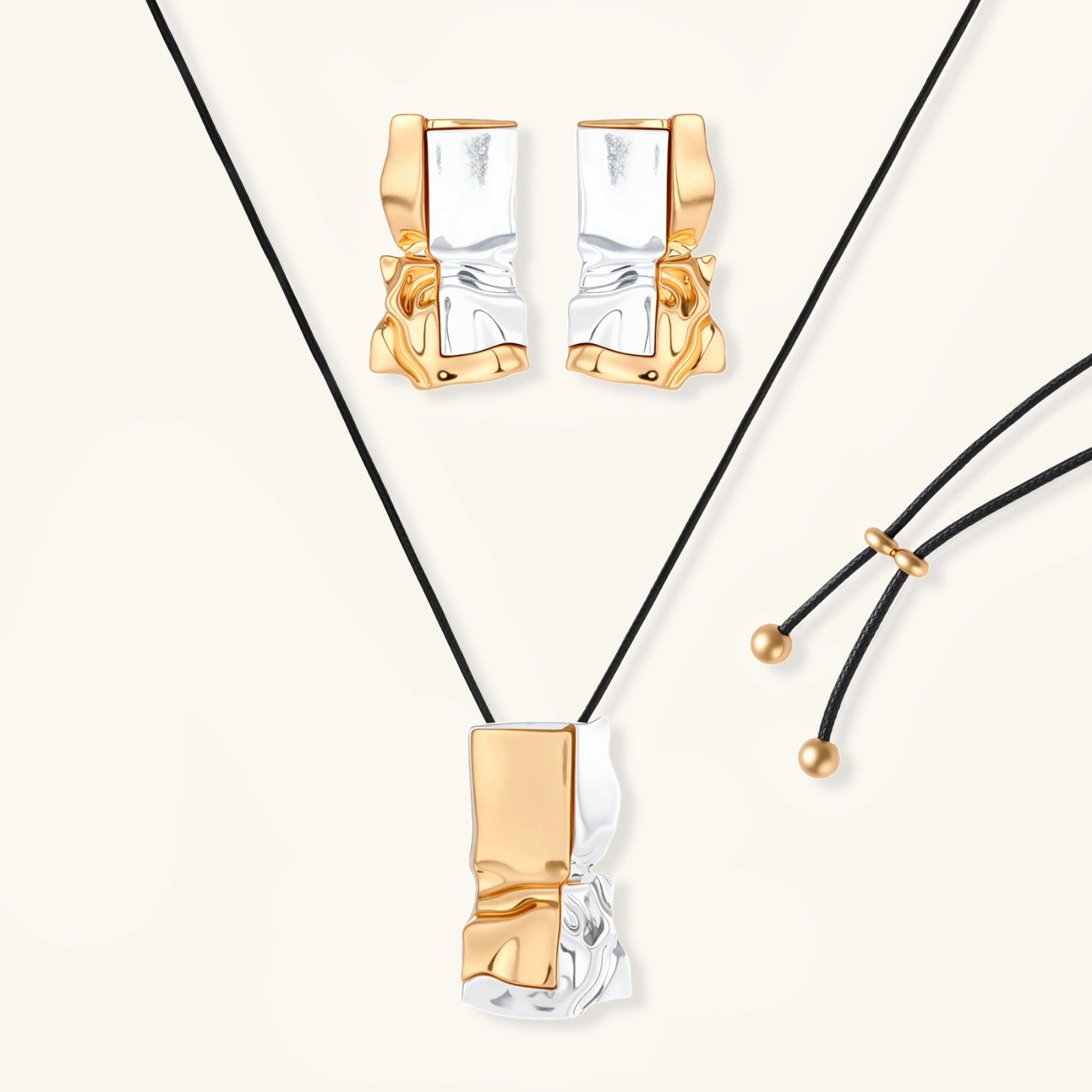 Modern jewelry set with abstract gold and silver pendant on black cord necklace plus matching geometric earrings on white background.