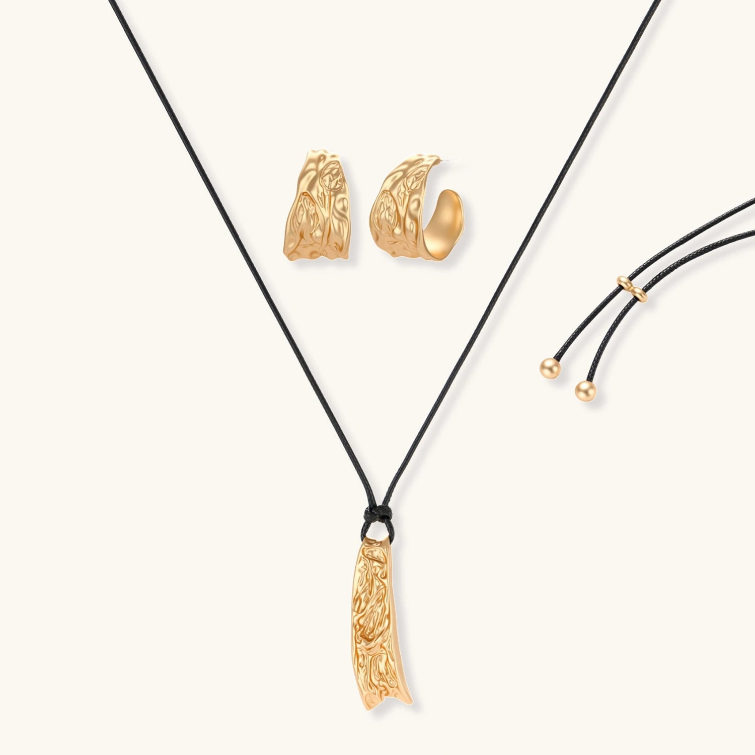 Gold-toned textured pendant necklace with matching hoop earrings featuring organic flowing patterns on white background.