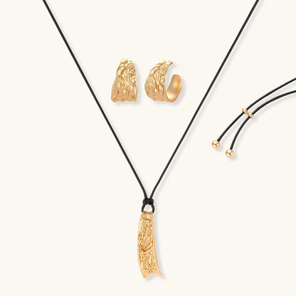 Gold-toned textured pendant necklace with matching hoop earrings featuring organic flowing patterns on white background.