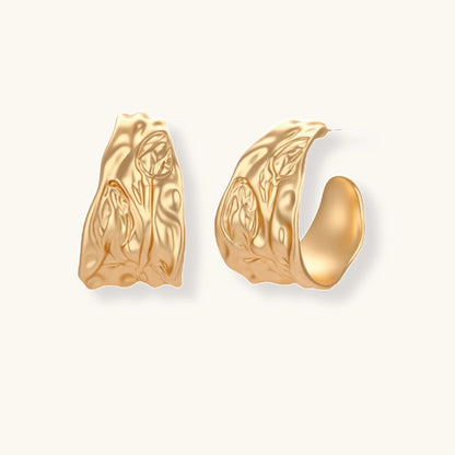 Gold-toned textured pendant necklace with matching hoop earrings featuring organic flowing patterns on white background.