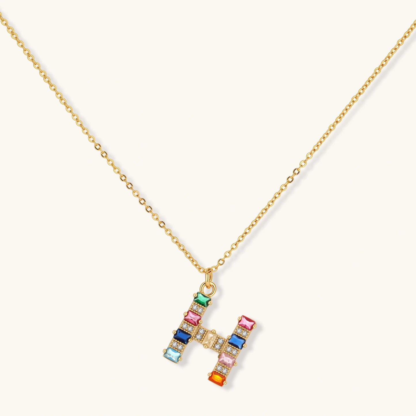 Gold-plated letter H jewelry set with multicolor zirconia stones in emerald cuts, showing necklace pendant and matching earrings