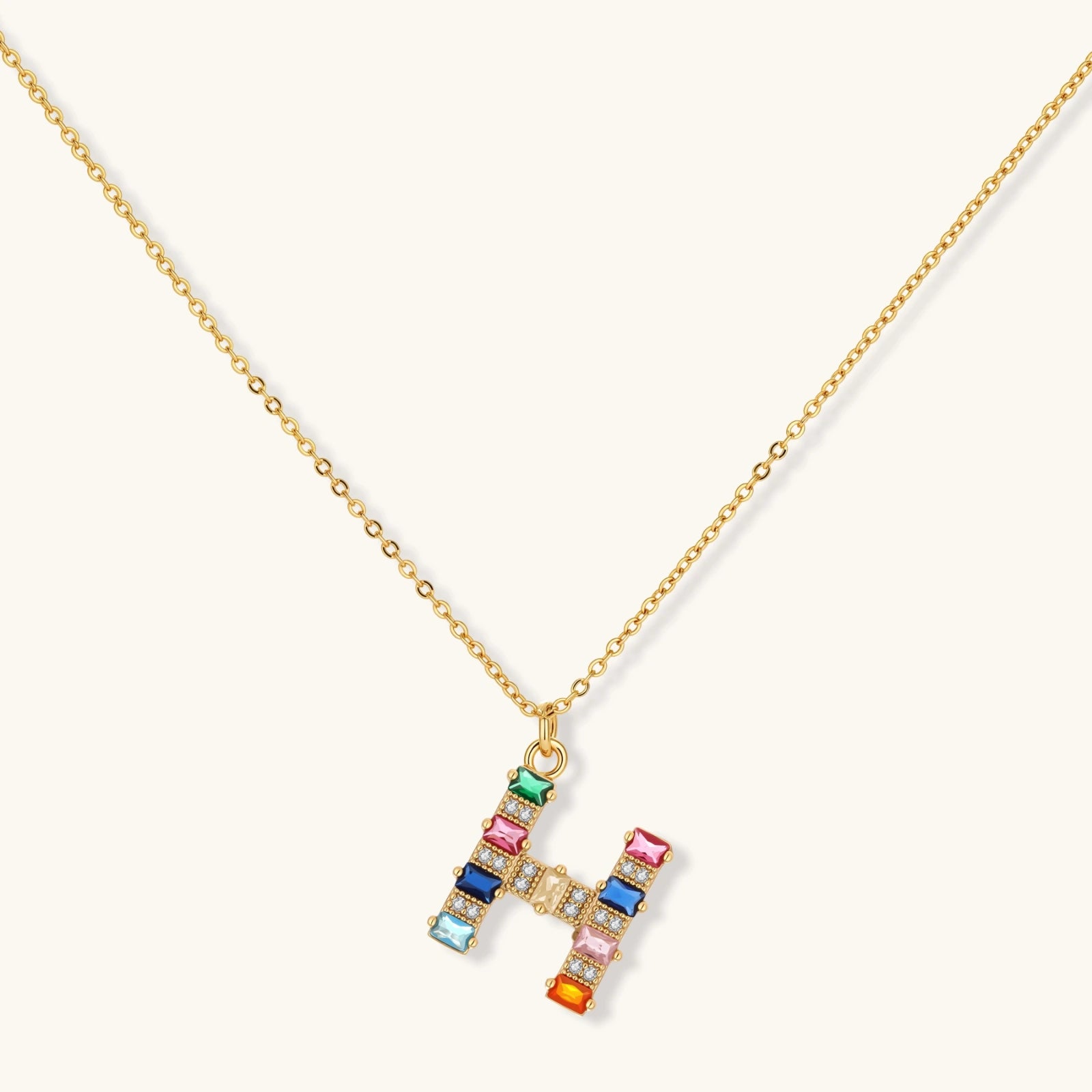 Gold-plated letter H jewelry set with multicolor zirconia stones in emerald cuts, showing necklace pendant and matching earrings